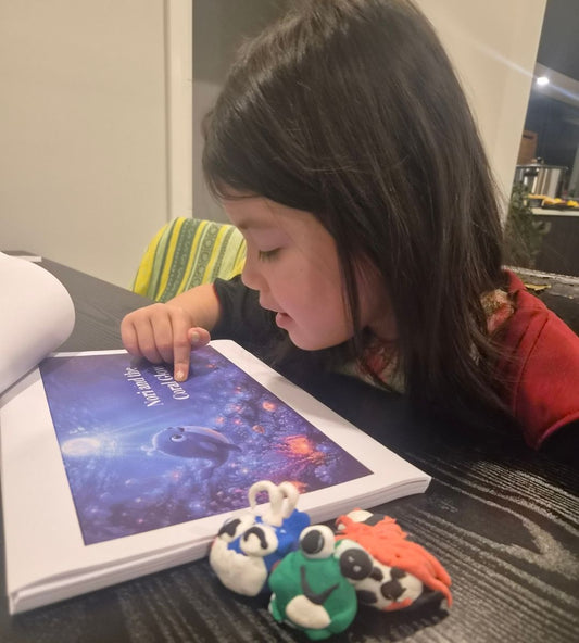 A child reading a Wild Wonderlands storybook with finished clay animals from the kit