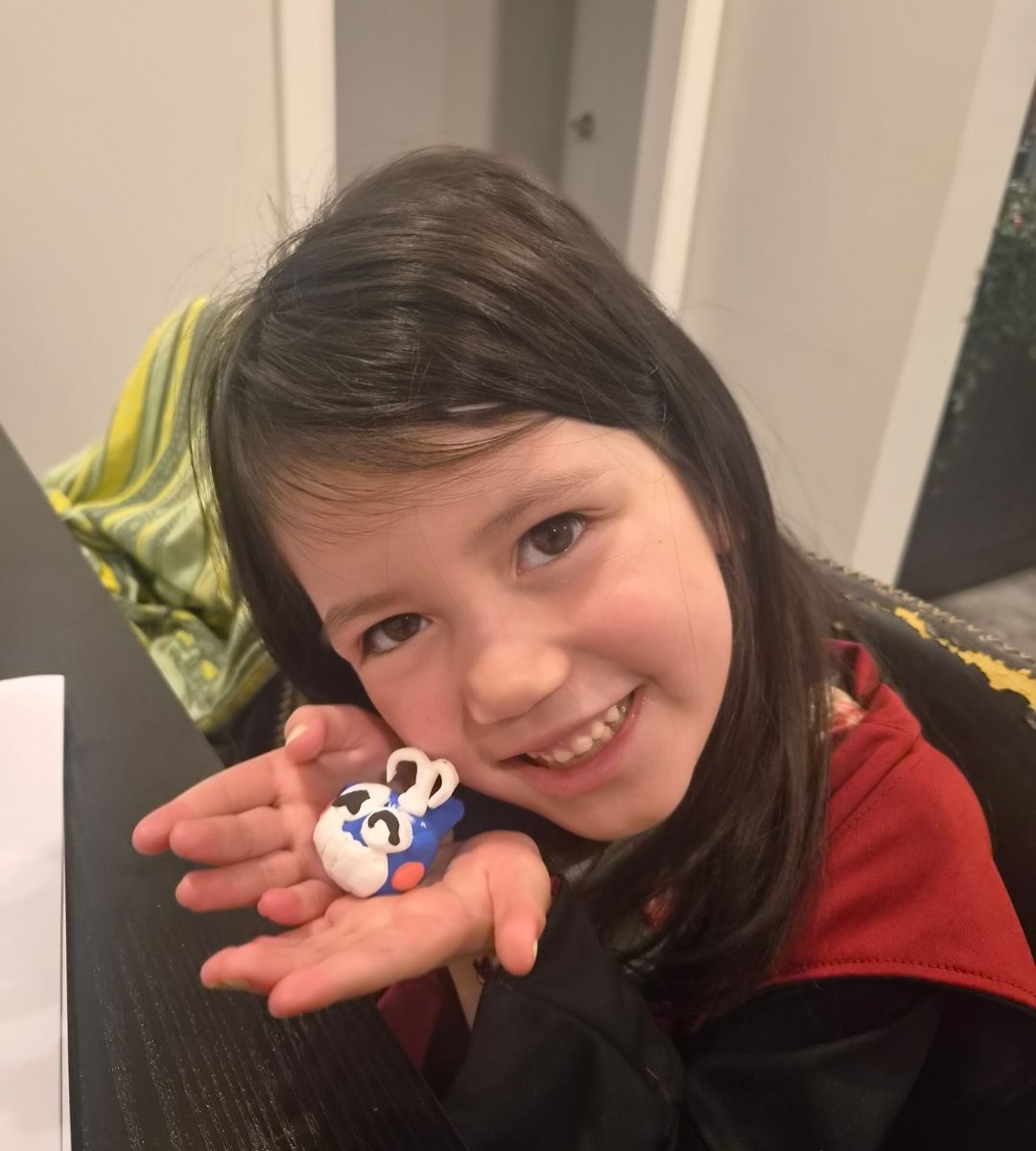 A child holding a clay animal she made from the 12 Animal Adventures Kit